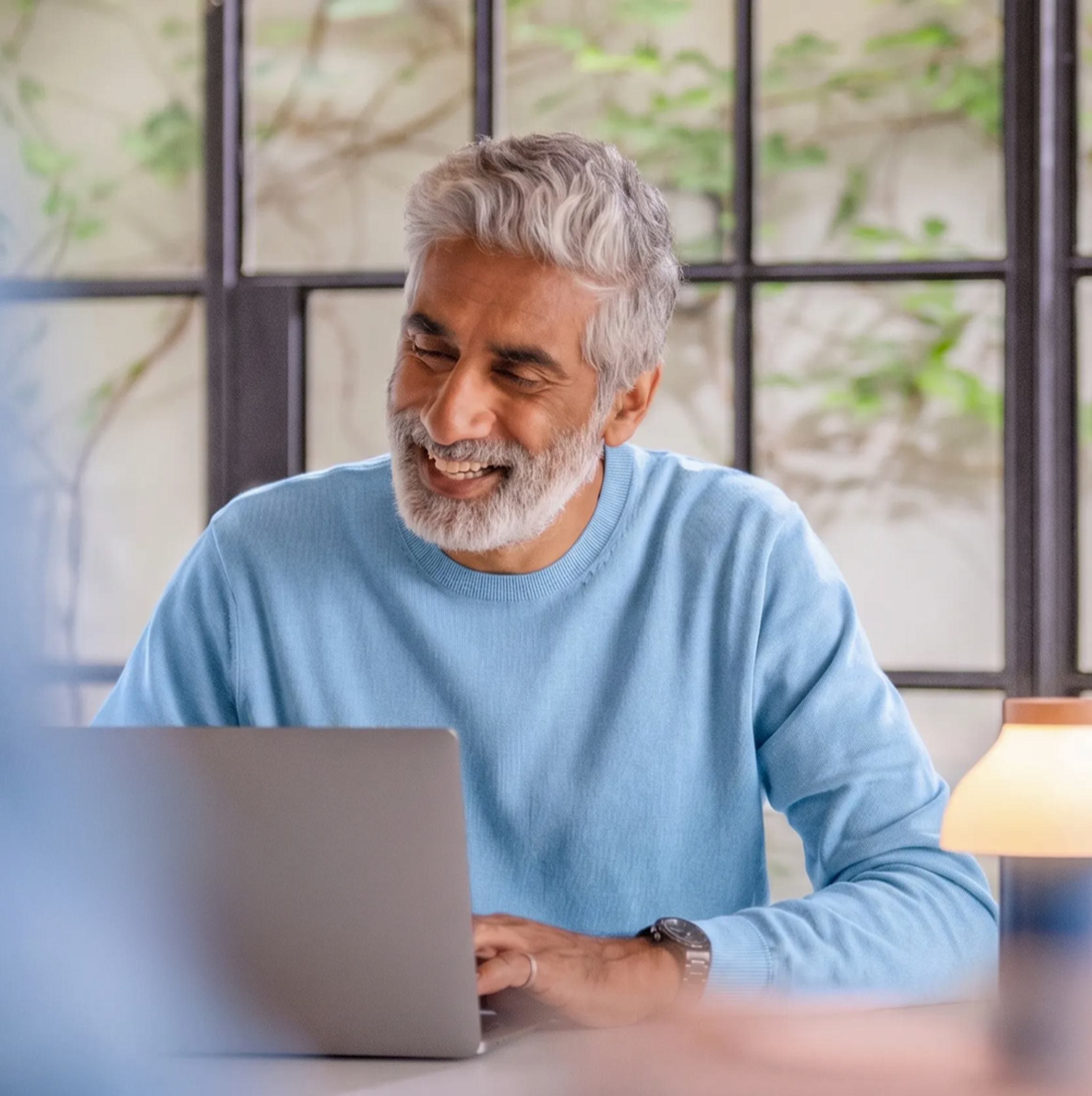 Proprietário sorrindo enquanto acompanha o imóvel pelo notebook